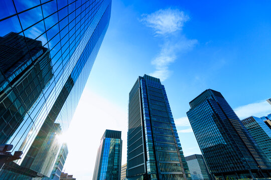 Abstract low-angle architectural view of glass skyscrapers in Tokyo with clear sky.