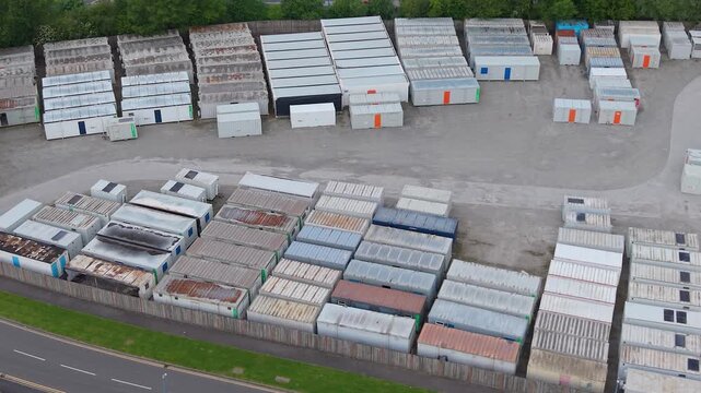 Rows of Stored Shipping Containers in Industrial Depot. Organized stacks of steel cargo containers. Surplus inventory, logistics management, massive scale of industrial storage solutions. Aerial. UK.