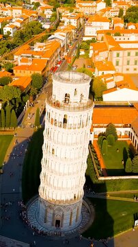 Vertical video. Pisa, Italy. The Leaning Tower of Pisa, its white marble Romanesque arcades rising from the manicured lawns of Piazza dei Miracoli, Drone footage in warm evening light. Drone footage.