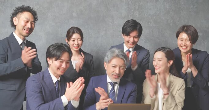 ノートパソコンの前に集合する様々な世代のスーツを着た男女