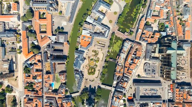 Metz, France. Drone footage over the historic city center, dense terracotta rooftops and the winding Moselle River gleaming under bright summer sunlight. Drone footage, HEAD OVER SHOT