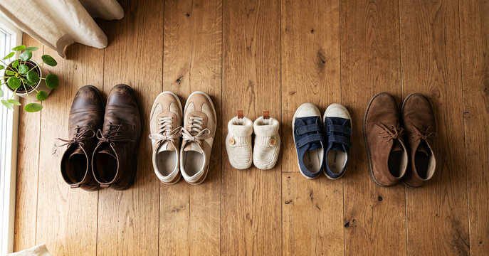 Top View of Different Family Member Shoes Lined Up in a Row on a Wooden Floor