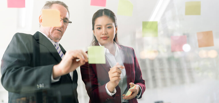 Business Team Brainstorming with Sticky Notes on Glass Board in Office Banner