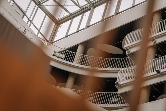 Modern architectural interior view of a multi-level building with curved balconies and large glass skylight overhead