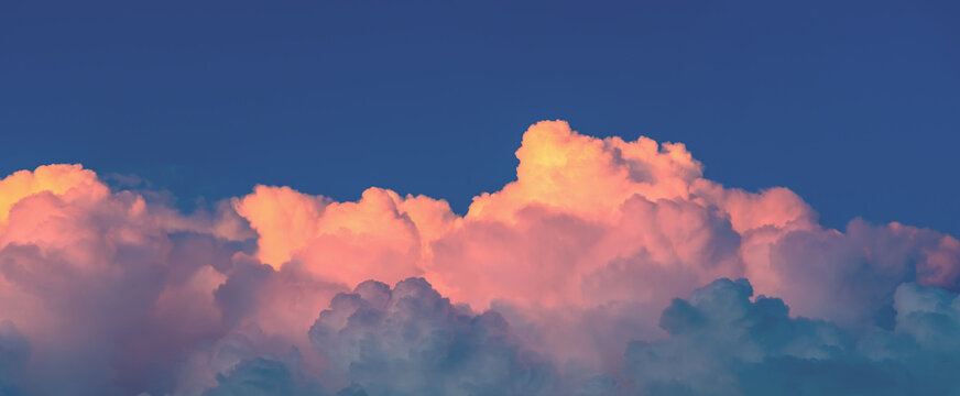 Vibrant sunset painting showcasing cumulus clouds illuminated in hues of gold and pink against a deep blue sky, creating a breathtaking and peaceful atmospheric spectacle
