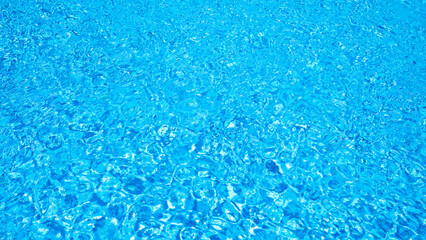 Sunlight reflecting on gently rippling water surface of a swimming pool creates a mesmerizing display of light and shadow, ideal for summer and travel themes © iloli