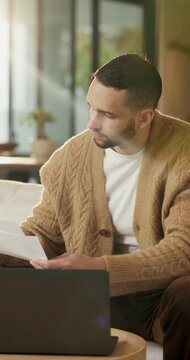Paperwork, reading and man with laptop for remote work, data entry and audit records for bookkeeping. Review, info evaluation or freelancer with computer to transcribe documents, home or check report
