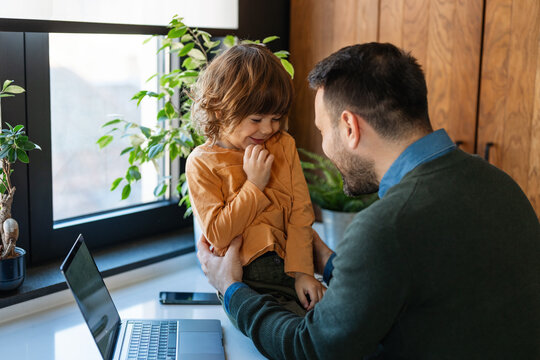 Single working dad spend time with small kid, sit together work on laptop. Happy family, parenthood