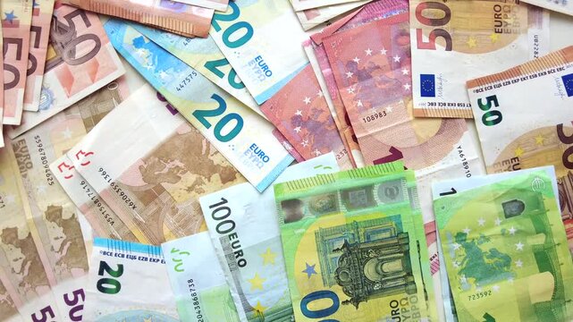 Euro banknotes scattered on flat surface showing variety of paper currency denominations.