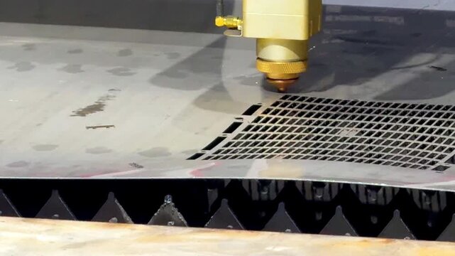 Laser cutting machine carving patterns on metal sheet with bright sparks