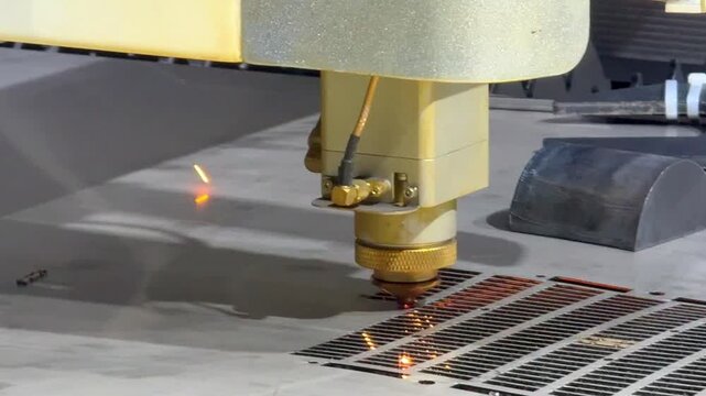 Laser cutting machine carving patterns on metal sheet with bright sparks