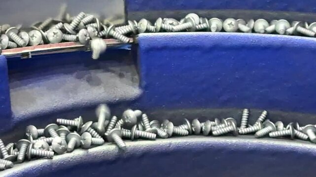 Vibratory boel feeder sorting screws on a conveyor belt for quality control inspection in an automated factory.	