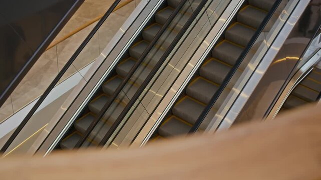 Side view no people shot of empty escalator staircases moving in different directions in modern shopping mall interior