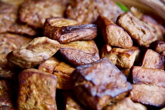 Close-up shot of traditional Indonesian braised sweet tofu and tempeh, known as tahu tempe bacem, showcasing a rich caramelized texture.