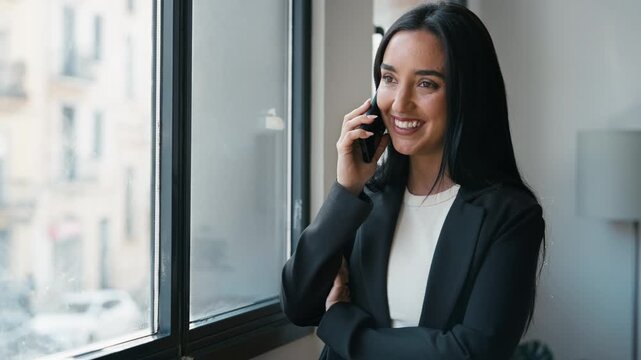 Video of smiling businesswoman talking with smartphone while standing in the office