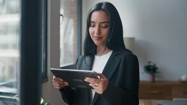 Video of elegant businesswoman working with digital tablet while standing in the office