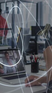Vertical video: Arm moving lamp using mouse sparking light rays sweeping over laptop on office call