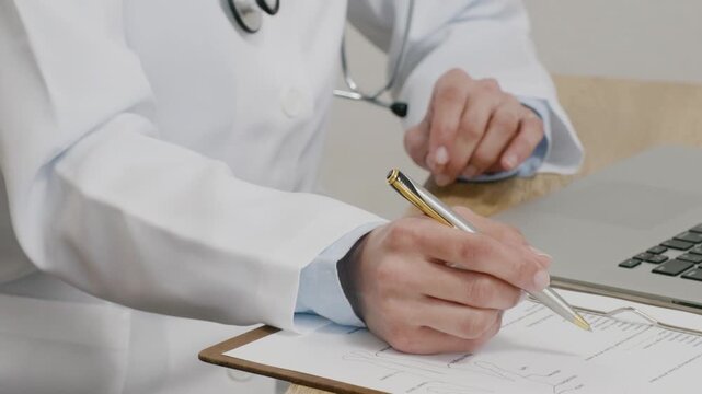 Close-up of Hands of Female Doctor Filling in Medical Questionnaire
