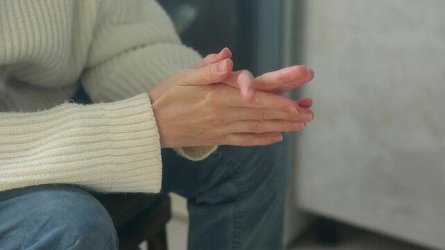 Close up nervous woman sitting and anxiously wringing her hands, displaying signs stress, worry, fear through her body language while waiting important outcome. Anxious woman wringing hands close up