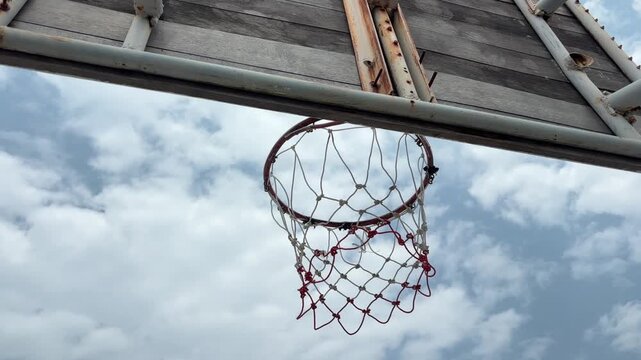 Old outdoor basketball hoop. View from back of wooden basketball backboard under a clear blue sky. Tilt down shot