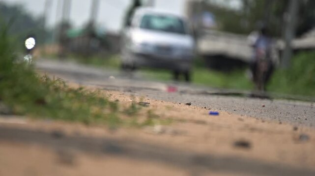 Intense Indian Summer Heat Wave with Blurred Car Driving on Shimmering Asphalt. Hot Dusty Roadside Surface. Ground Level View of Sun-Baked Indian Roadside.