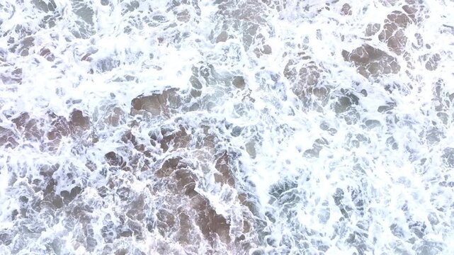 Waves forming white foam. Sea waves in constant motion. Ocean water in motion. Sea waves spreading on sand.