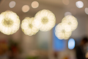 Abstract blurred background beautiful warm golden bokeh lights shaped like glowing flowers from interior decorative lighting. Perfect for elegant celebration, luxury, and festive holiday concepts. © kaew6566