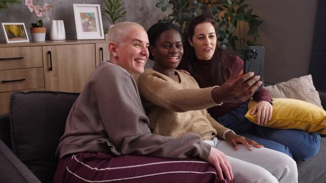 Cheerful multiethnic female friends taking selfies on a smartphone