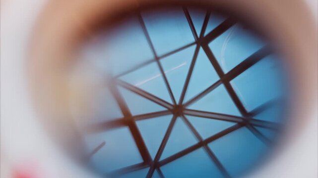 Abstract view through glass circle showing geometric skylight structure.