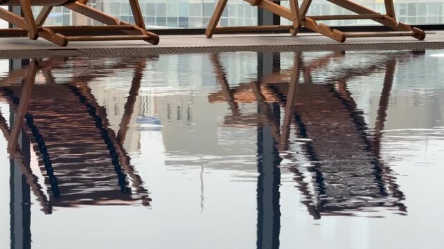 Wooden loungers and their reflection in a spa pool, creating symmetrical calm and tranquil luxury atmosphere.