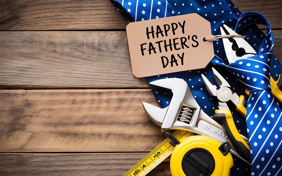 Happy fathers day greeting card with blue polka dot necktie and various construction tools on a rustic wooden background