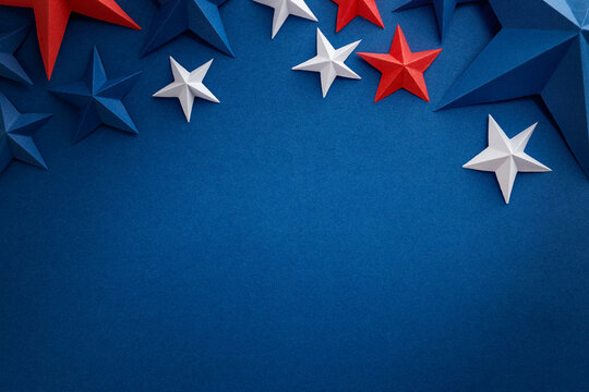 Red white and blue paper stars with curled ribbons on blue background, patriotic holiday border with copy space. Design element.