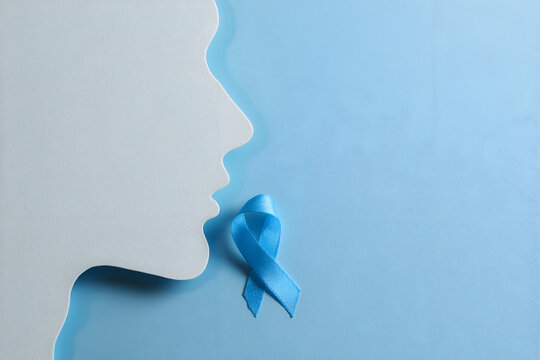 Paper cutout of man's profile holding blue awareness ribbon, minimal blue background.