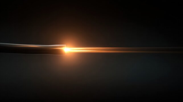 Optical Fiber Light Transmission: A single strand of optical fiber cable glows with vibrant orange light, conveying data and speed in a dark, abstract setting.