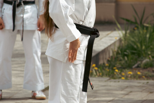 A karateka in a white kimono with a black belt throws punches.