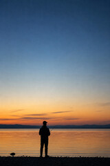 Fototapeta premium Silhouette of Fisherman at Calm Lake During Sunset