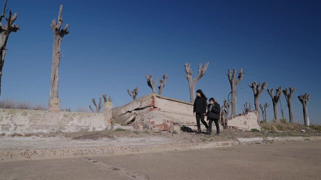 Mother and Daughter Walking Past Abandoned Building Ruins and Dead Trees in Epecuén, Argentina Buenos Aires