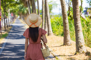 Fototapeta premium Back view of woman with hat walking in sunny park