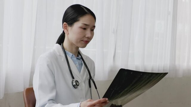 Asian Female Doctor in White Coat Reviewing X-ray Image