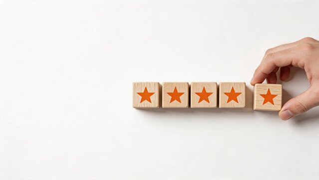 Hand placing wooden block with orange star to complete five star rating concept for customer satisfaction, review, quality service, and feedback evaluation.