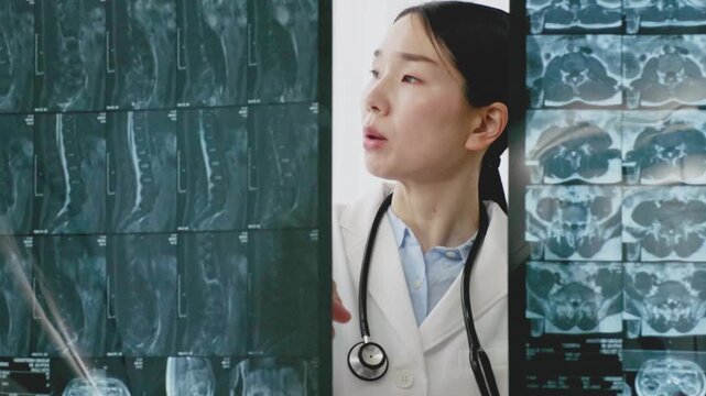 Asian Female Doctor in White Coat Reviewing X-ray Image