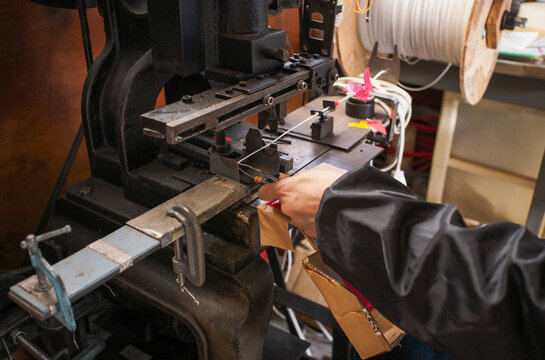 Close-up of vintage industrial press machine processing lead wire in traditional small factory
