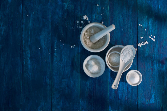 Bowls of different sorts of salt on blue wood