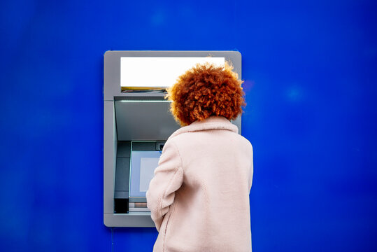 Mid adult woman with afro hair using kiosk in city