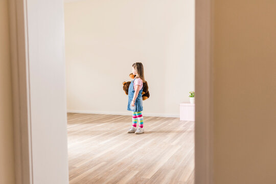 Girl in empty apartment holding teddy