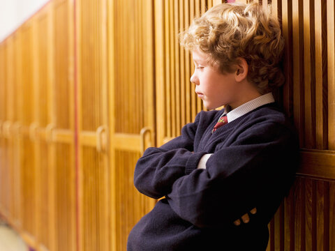 Boy (4-7) standing and leaning on locker, side view, close-up