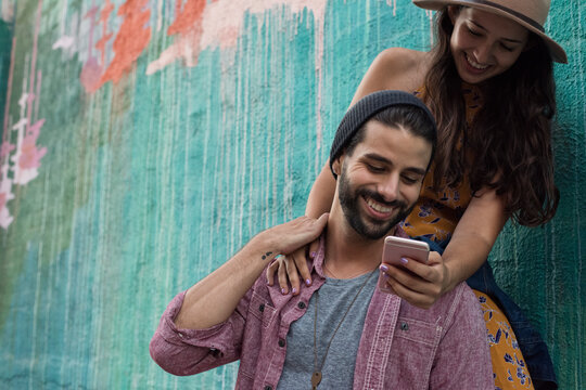Happy young couple with cell phone outdoors