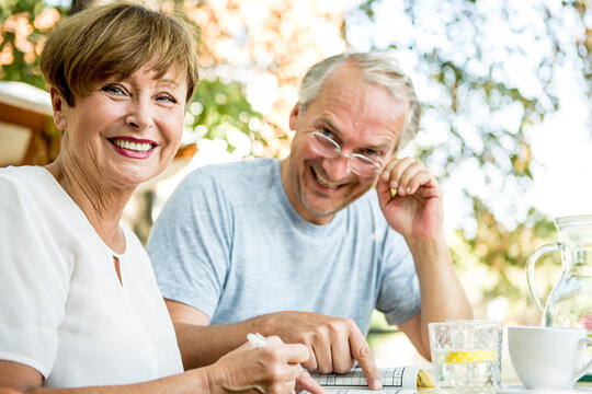 Smiling senior couple outdoors doing crossword puzzle together