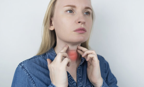 Woman touching sore neck and thyroid gland area, suffering from pain, goiter, throat infection or Venus wrinkles. Medical healthcare and endocrinology concept.