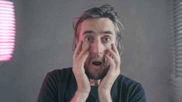 Mind-blown shock surprise emotion gesture Indoor video of a dark-haired bearded man showing astonishment, frustration, and expressive facial expressions hand gestures against a neutral background
